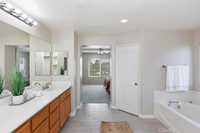 bathroom with vanity, baseboards, a bath, visible vents, and ceiling fan
