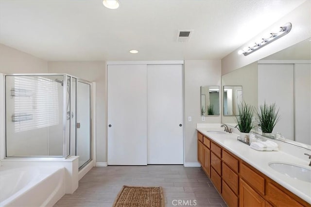 full bathroom with a sink, visible vents, a stall shower, and wood finished floors