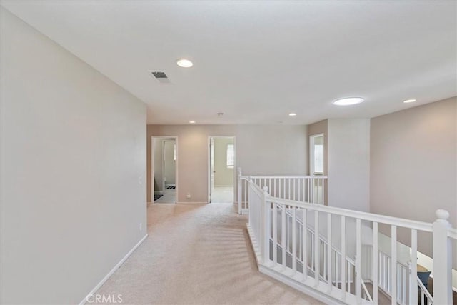 hall with visible vents, baseboards, an upstairs landing, carpet floors, and recessed lighting