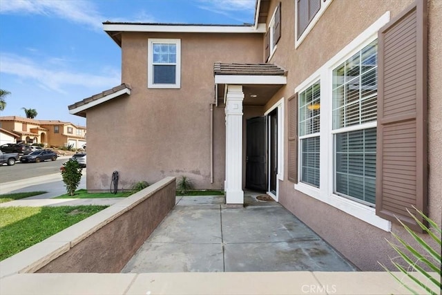 property entrance with a tile roof and stucco siding
