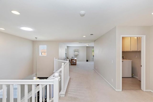 hallway featuring washer / clothes dryer, light colored carpet, recessed lighting, an upstairs landing, and baseboards