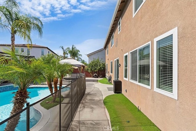 view of home's exterior with a patio area, fence, a fenced in pool, and stucco siding