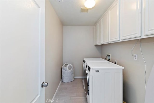 laundry room with baseboards, light wood-style floors, visible vents, cabinet space, and washer and dryer