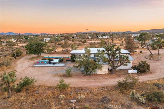 aerial view at dusk featuring a rural view, a mountain view, and view of desert