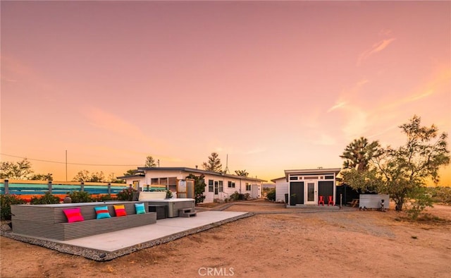 back of house at dusk featuring an outbuilding and a patio area