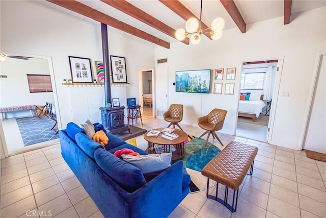tiled living room featuring a wood stove, visible vents, ceiling fan with notable chandelier, and vaulted ceiling with beams