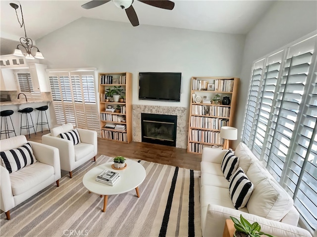 living room with a ceiling fan, wood finished floors, a tile fireplace, and lofted ceiling