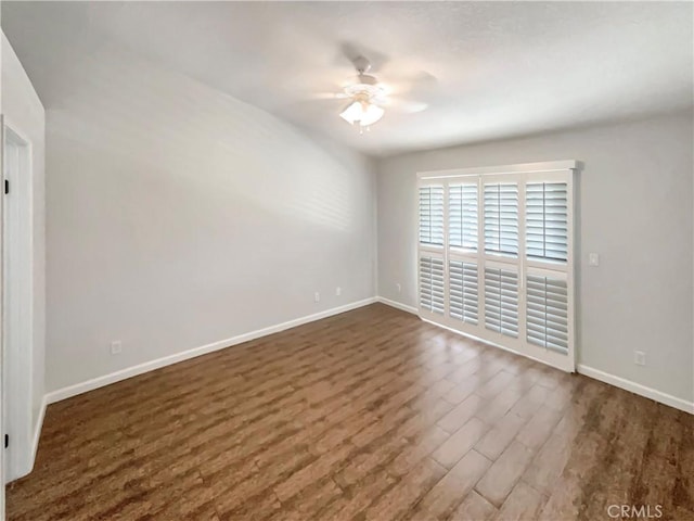 unfurnished room featuring ceiling fan, baseboards, and dark wood finished floors