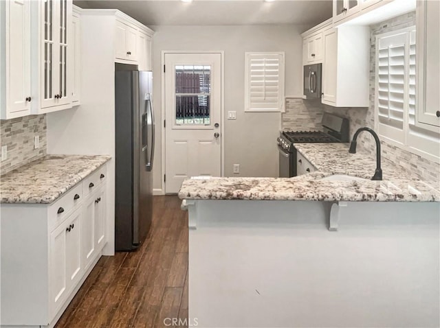 kitchen with dark wood-type flooring, white cabinetry, glass insert cabinets, and stainless steel appliances