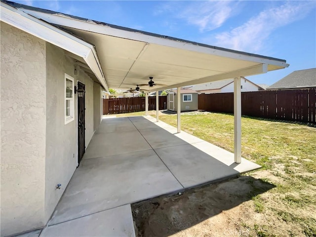 view of patio / terrace featuring a shed, a fenced backyard, a ceiling fan, and an outbuilding
