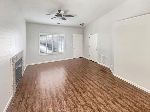 unfurnished living room with visible vents, baseboards, ceiling fan, dark wood-style floors, and a glass covered fireplace