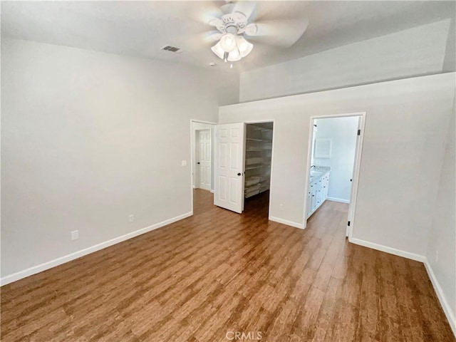 unfurnished bedroom featuring a closet, a spacious closet, visible vents, wood finished floors, and baseboards