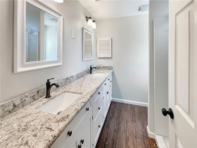 full bathroom featuring a sink, baseboards, double vanity, and wood finished floors