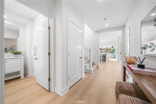312 Carefree, Irvine, CA 92618 - hallway with light wood-style flooring, recessed lighting, stairway, a sink, and baseboards