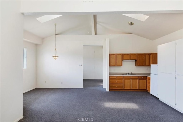 kitchen featuring brown cabinetry, beamed ceiling, dark carpet, and a skylight