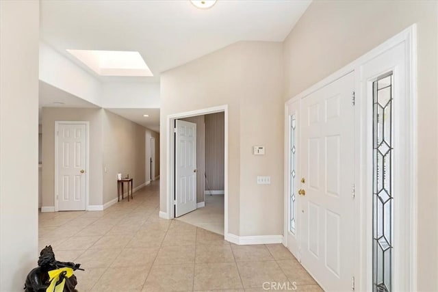 entryway with a skylight, light tile patterned floors, and baseboards