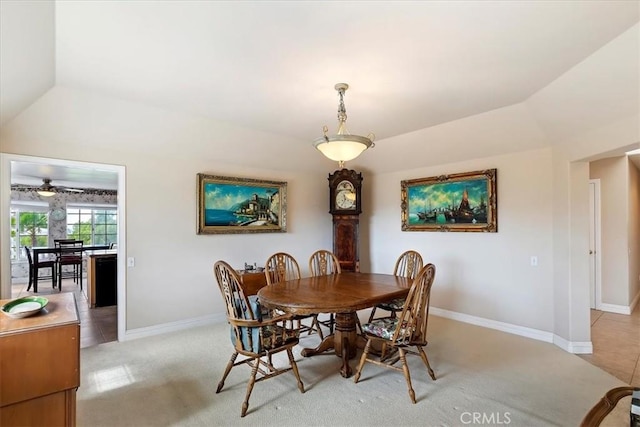 dining area with baseboards, light colored carpet, and vaulted ceiling