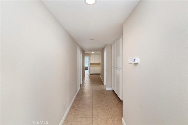 hallway with light tile patterned floors and baseboards