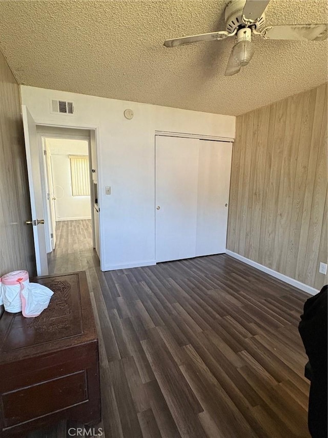 3670 Upper Terrace Dr, Riverside, CA 92505 - unfurnished bedroom featuring a textured ceiling, wooden walls, baseboards, dark wood-type flooring, and a ceiling fan