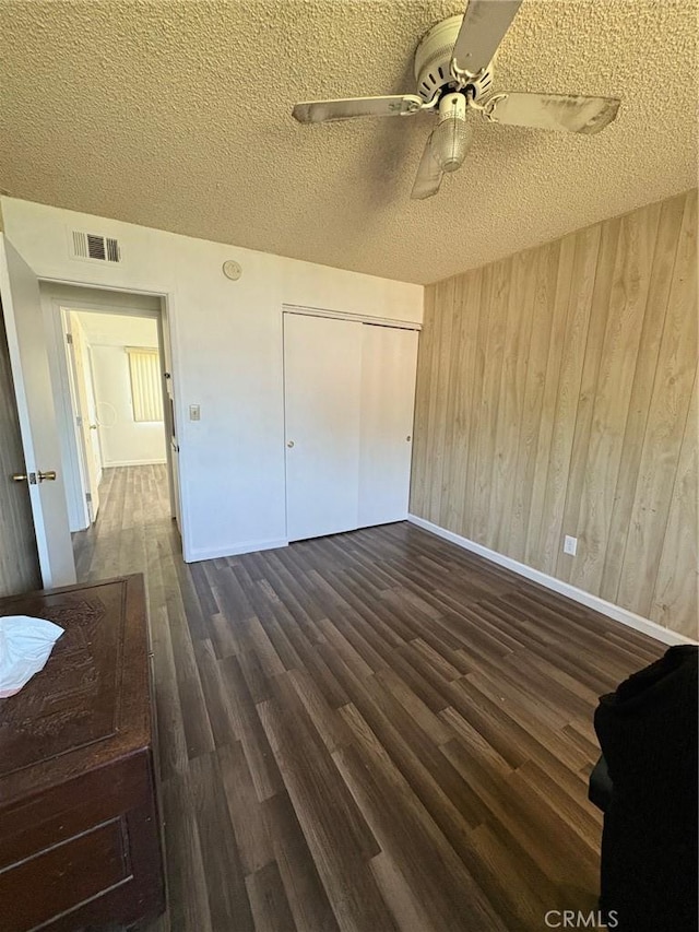 3670 Upper Terrace Dr, Riverside, CA 92505 - unfurnished bedroom featuring a textured ceiling, baseboards, dark wood-type flooring, wooden walls, and ceiling fan