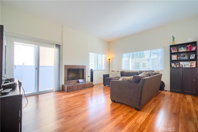 living room with light wood-type flooring and a tiled fireplace