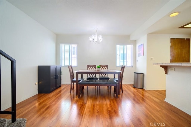 dining room featuring light wood-style flooring, an inviting chandelier, and baseboards