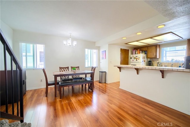 dining space featuring recessed lighting, light wood-style floors, baseboards, and an inviting chandelier