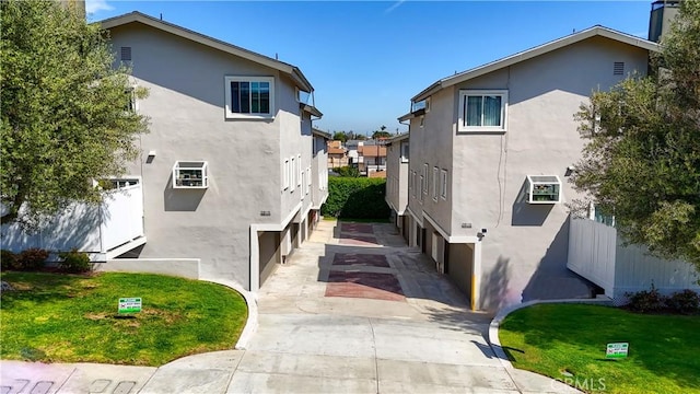 view of side of property featuring a yard, driveway, stucco siding, and an attached garage