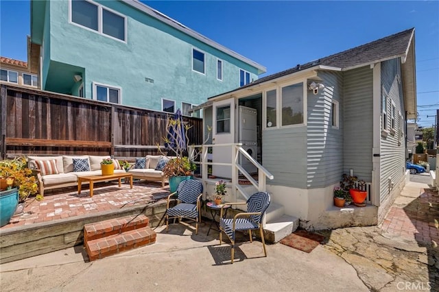 rear view of property featuring outdoor lounge area, a patio area, and fence
