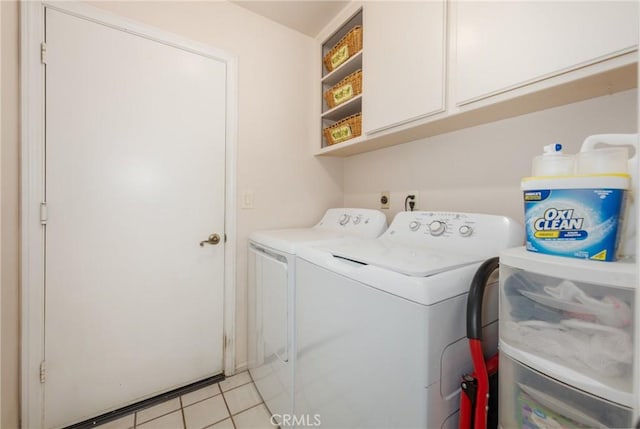 washroom featuring washer and dryer, light tile patterned flooring, and cabinet space