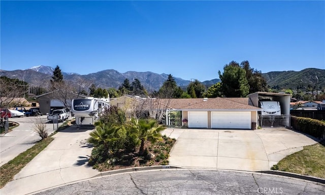view of front facade with a mountain view, fence, and concrete driveway