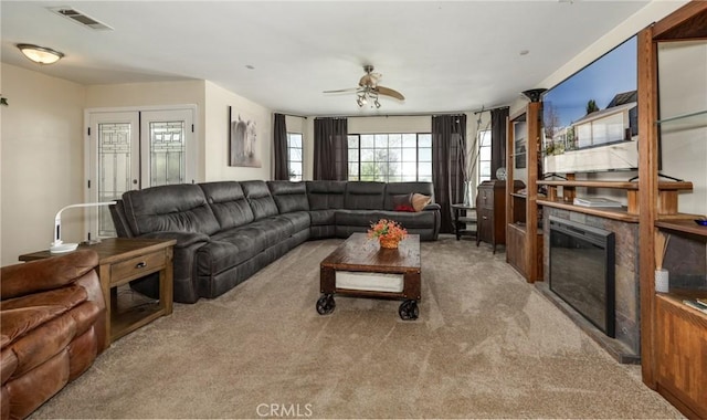 carpeted living area featuring a glass covered fireplace, a ceiling fan, and visible vents