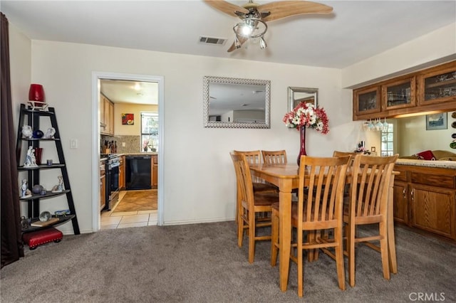 dining space with light tile patterned floors, visible vents, light colored carpet, and ceiling fan