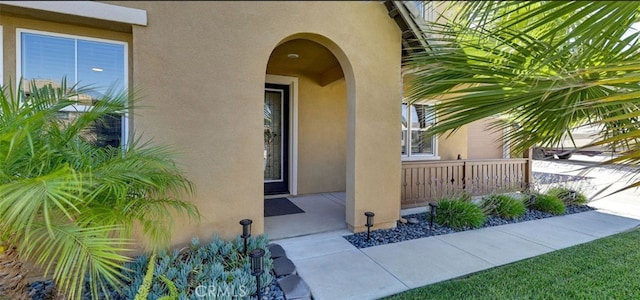 view of exterior entry featuring covered porch and stucco siding