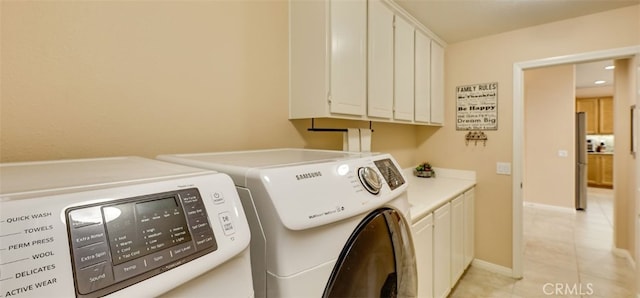 laundry room featuring separate washer and dryer, baseboards, light tile patterned flooring, and cabinet space