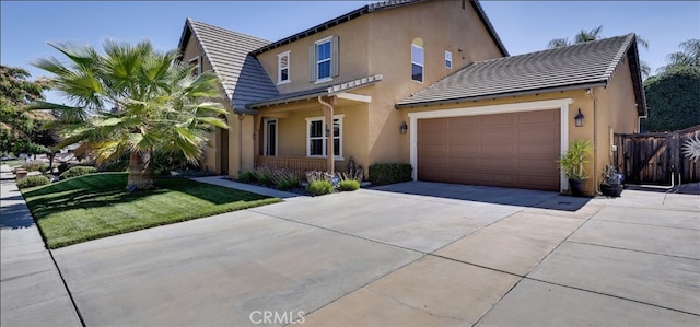 view of front of house with concrete driveway, a tile roof, fence, and stucco siding