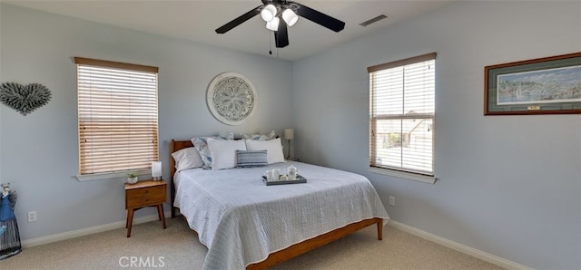 carpeted bedroom with visible vents, baseboards, and a ceiling fan
