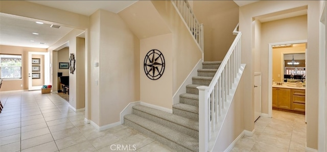 stairs with visible vents, baseboards, an inviting chandelier, and tile patterned flooring