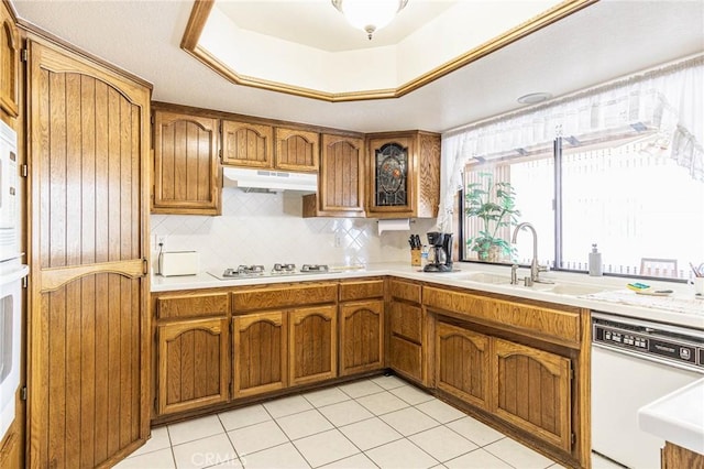 7040 Kenyon Ave, Hesperia, CA 92345 - kitchen featuring tasteful backsplash, light countertops, white appliances, under cabinet range hood, and brown cabinets