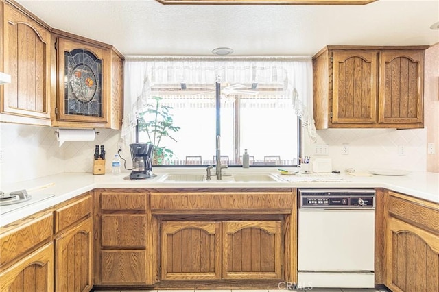 7040 Kenyon Ave, Hesperia, CA 92345 - kitchen with white dishwasher, a sink, light countertops, brown cabinets, and decorative backsplash