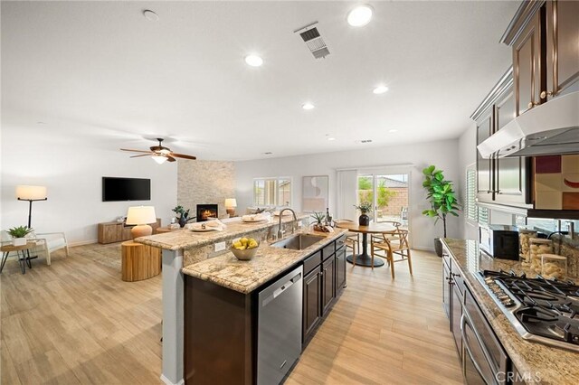 73992 Van Gogh Dr, Palm Desert, CA 92211 - kitchen featuring a sink, stainless steel appliances, a fireplace, ceiling fan, and light wood-type flooring