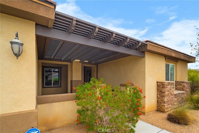 73992 Van Gogh Dr, Palm Desert, CA 92211 - property entrance with a pergola, stucco siding, and stone siding