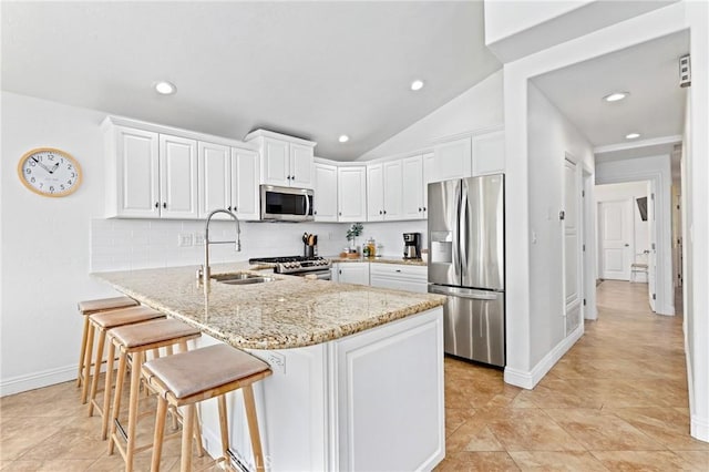kitchen featuring white cabinets, a peninsula, a sink, tasteful backsplash, and appliances with stainless steel finishes