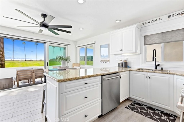 kitchen featuring a peninsula, white cabinetry, a ceiling fan, a sink, and light wood finished floors