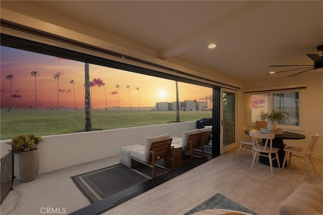 sunroom / solarium featuring beam ceiling and a ceiling fan