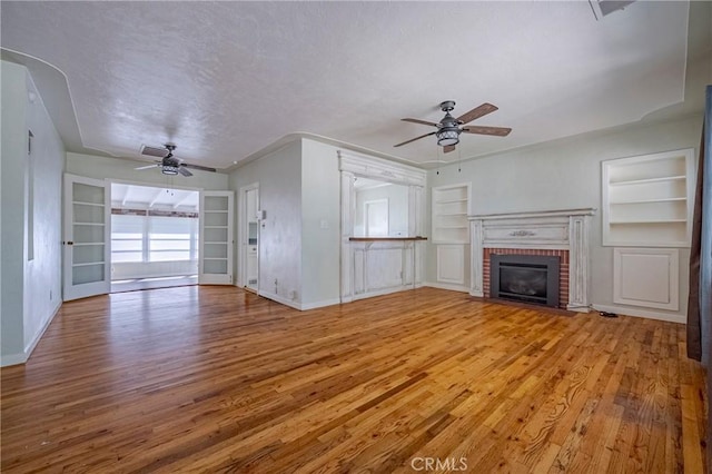 2550 5th Ave, Merced, CA 95340 - unfurnished living room with baseboards, a ceiling fan, a brick fireplace, built in shelves, and light wood finished floors