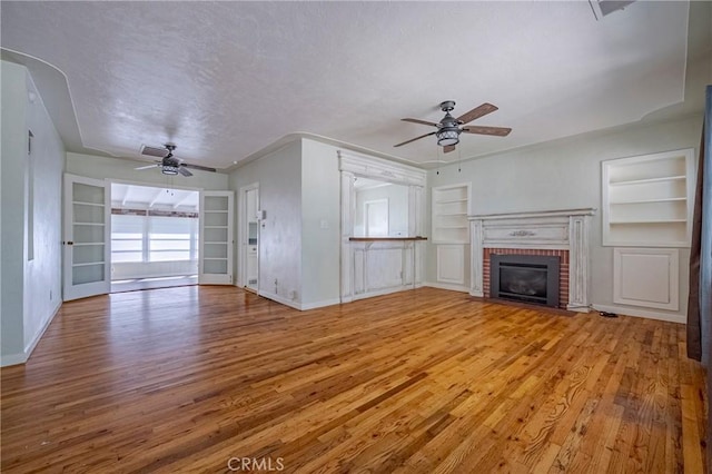 2550 5th Ave, Merced, CA 95340 - unfurnished living room with ceiling fan, built in features, light wood-style flooring, a fireplace, and a textured ceiling