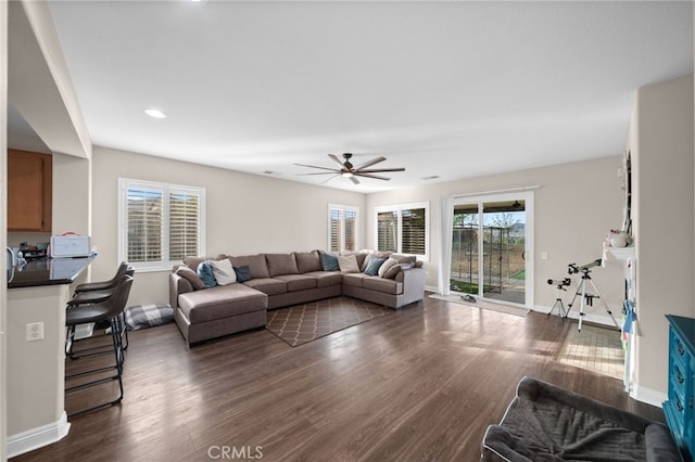 living room featuring dark wood-style flooring, ceiling fan, and a wealth of natural light