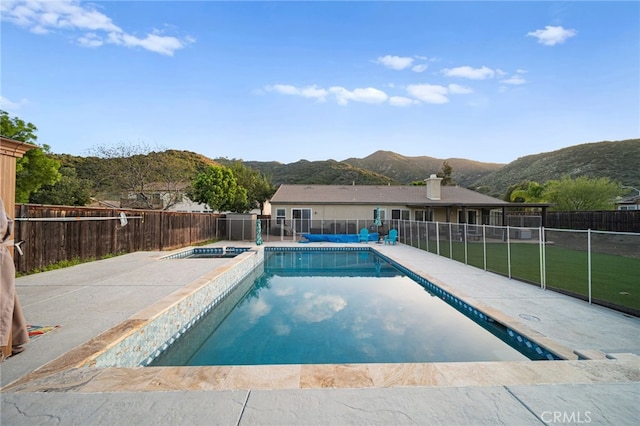 view of swimming pool featuring an in ground hot tub, a patio area, a fenced in pool, a mountain view, and a fenced backyard