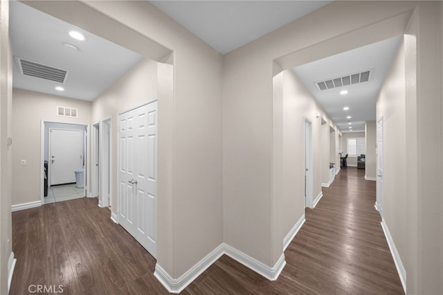 hallway featuring baseboards, visible vents, and dark wood-style floors
